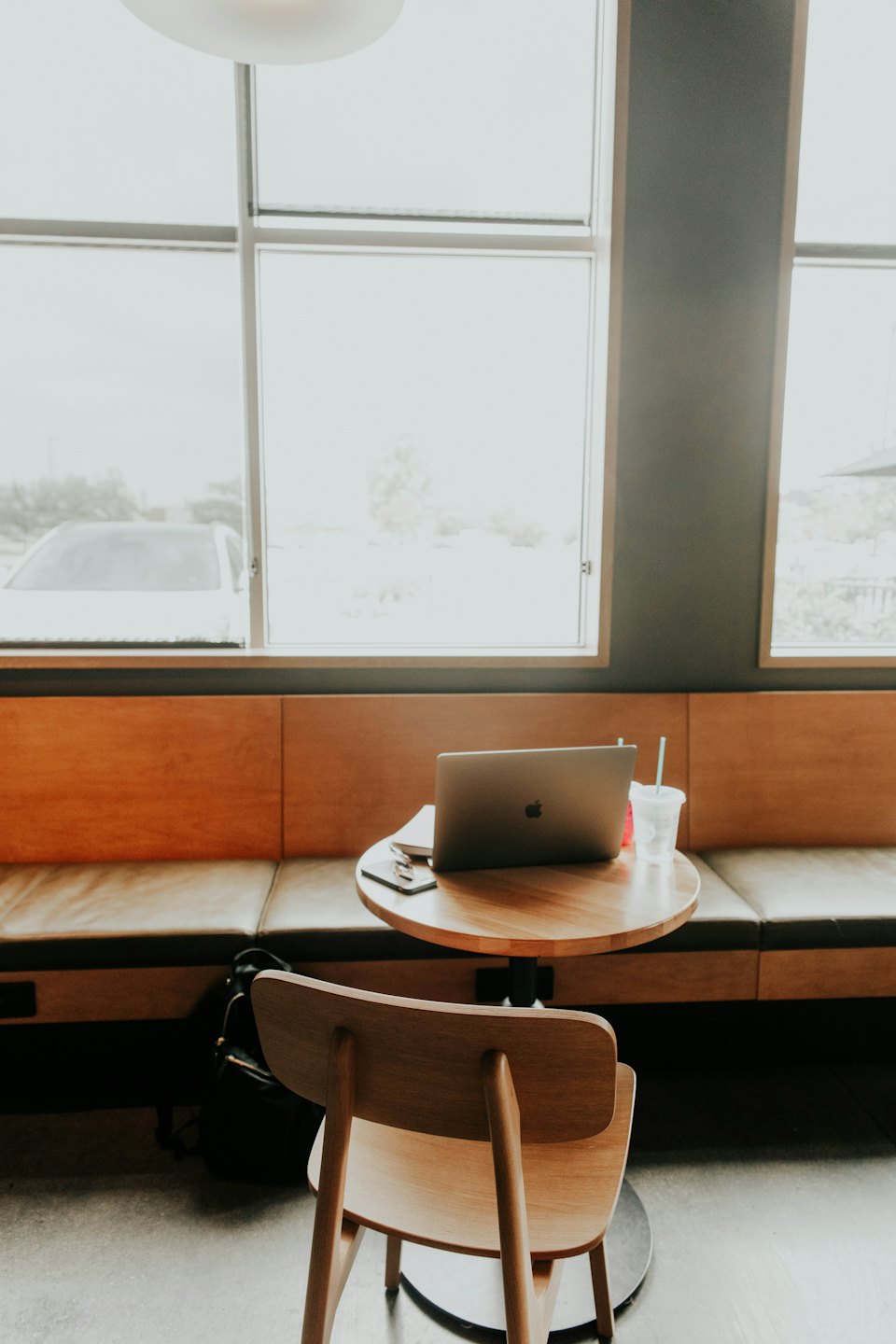 Laptop, phone, and drink on a wooden table in a cafe.