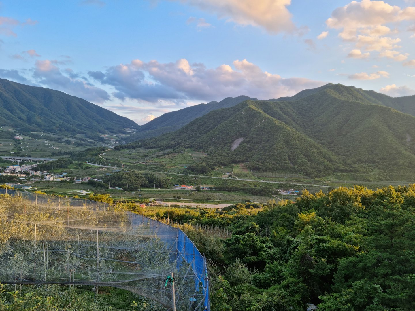 Houses and farmland sit in a sunlit mountain valley.