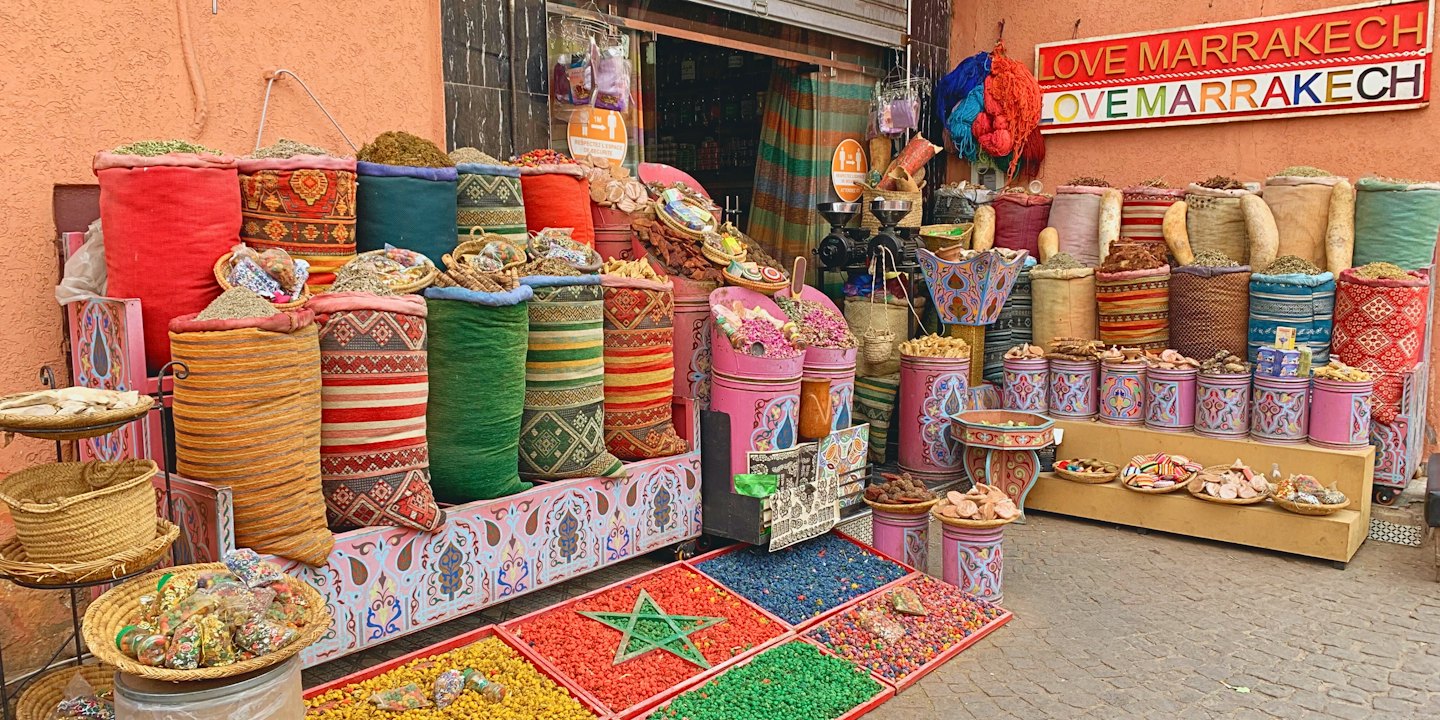Outdoor market stall selling colorful spices and herbs.